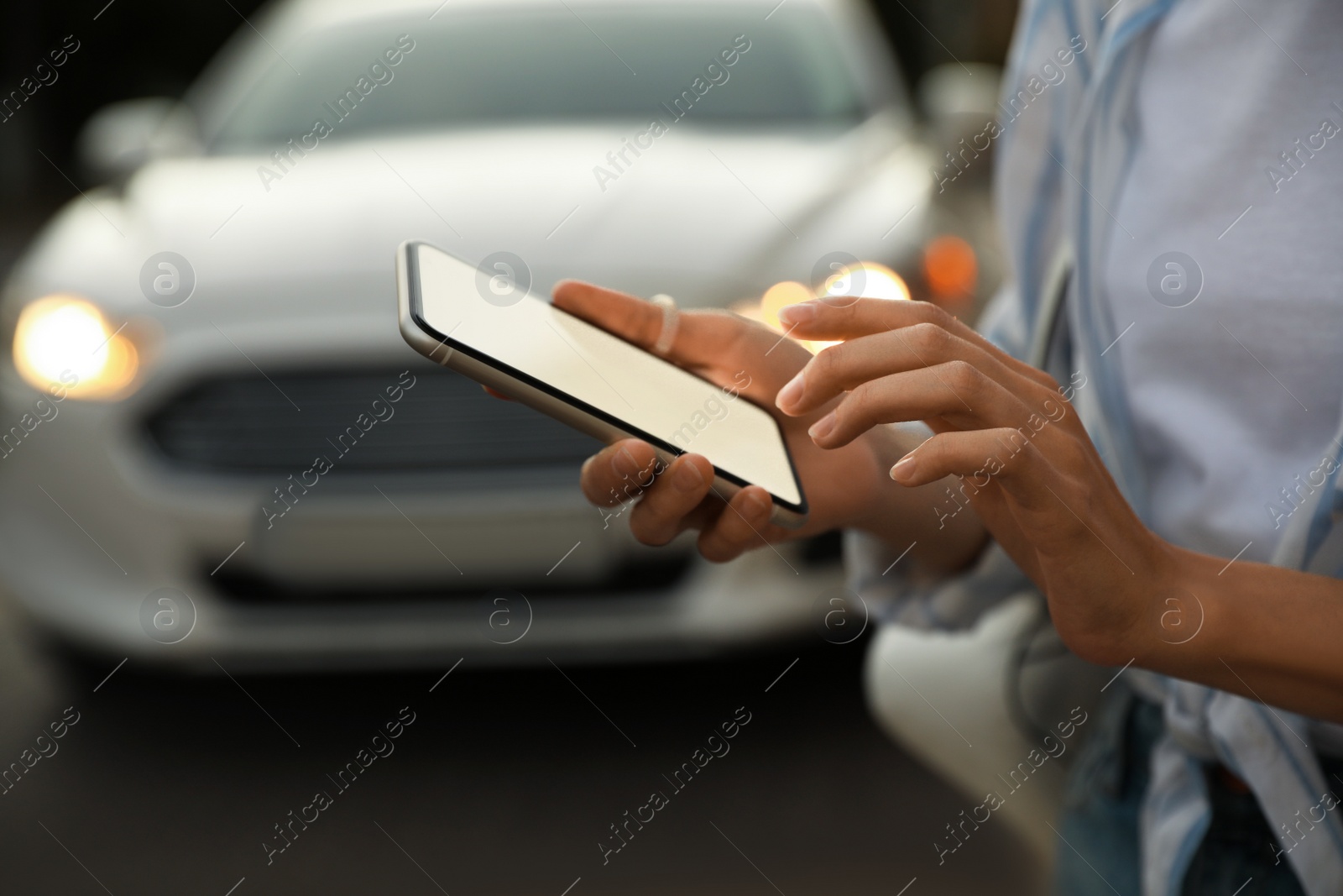 Photo of Woman ordering taxi with smartphone on city street, closeup