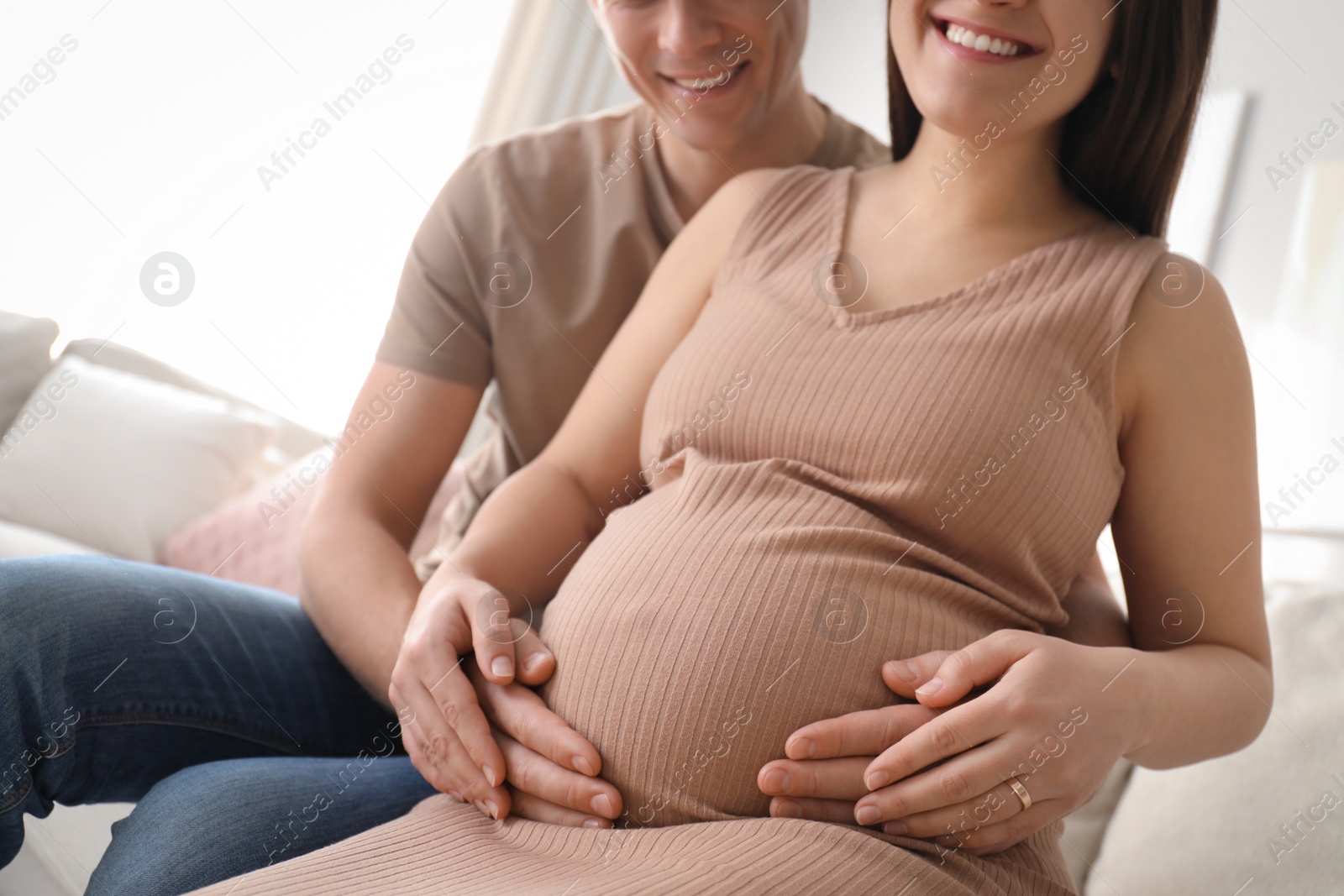 Photo of Man touching his pregnant wife's belly at home, closeup