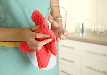 Photo of Woman wiping glass with towel in kitchen, closeup. Space for text