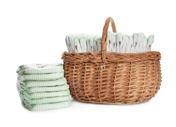 Photo of Wicker basket and disposable diapers on white background. Baby accessories