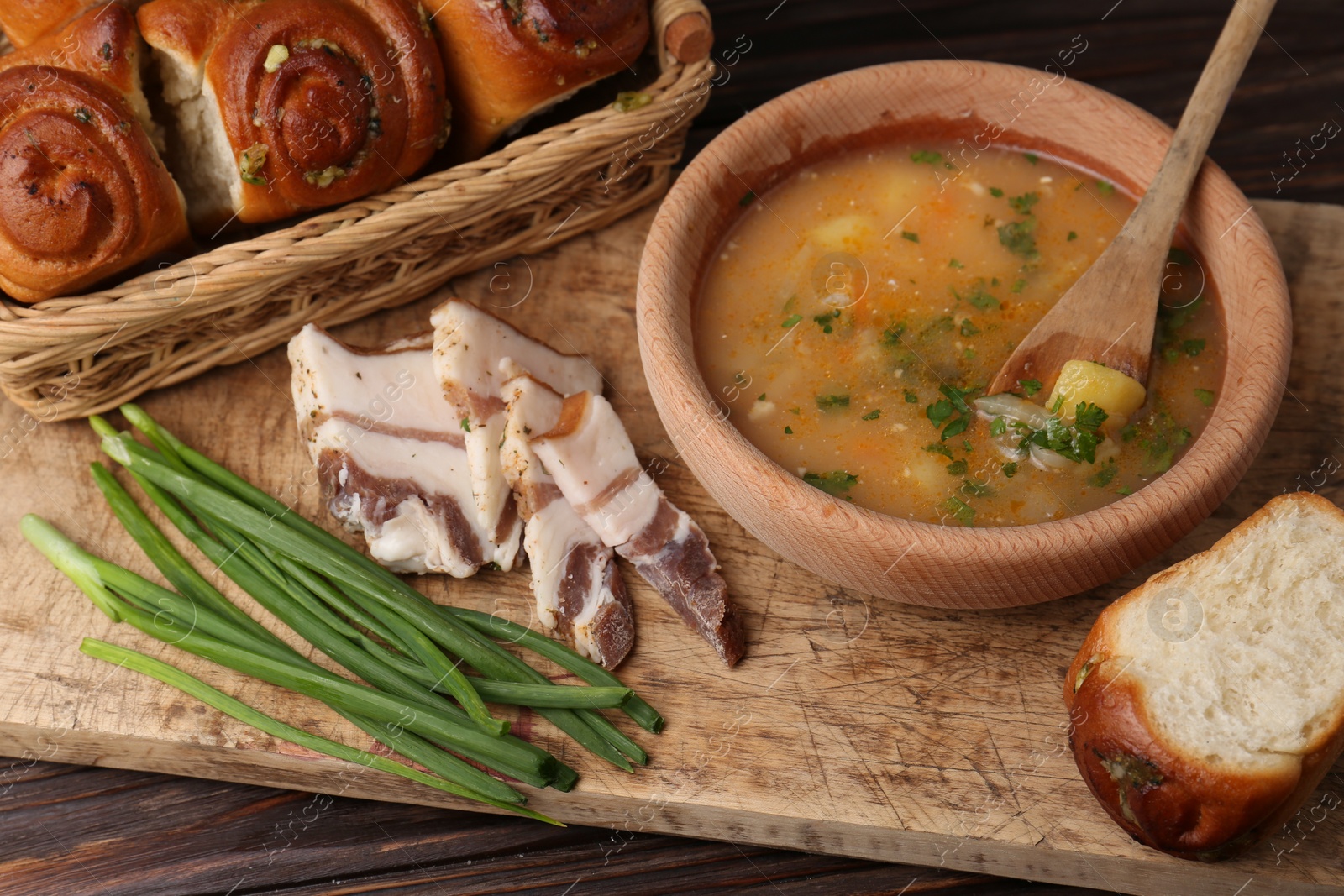 Photo of Delicious borsch served with pampushky and salo on wooden table. Traditional Ukrainian cuisine