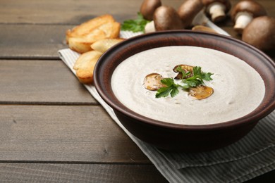 Fresh homemade mushroom soup in ceramic bowl on wooden table. Space for text