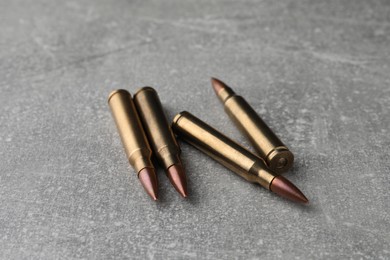 Photo of Bullets on light grey table, closeup. Firearm ammunition