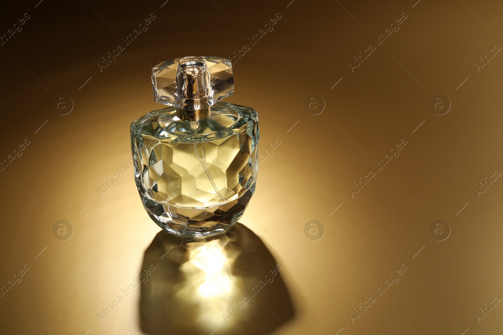 Photo of Luxury women's perfume. Sunlit glass bottle on golden background, space for text