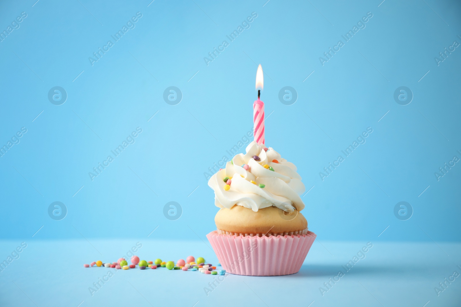 Photo of Delicious birthday cupcake with candle on light blue background