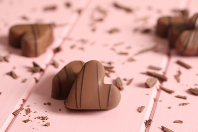 Beautiful heart shaped chocolate candies on pink wooden table, closeup