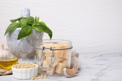 Different ingredients for cooking tasty pesto sauce on white marble table, closeup. Space for text