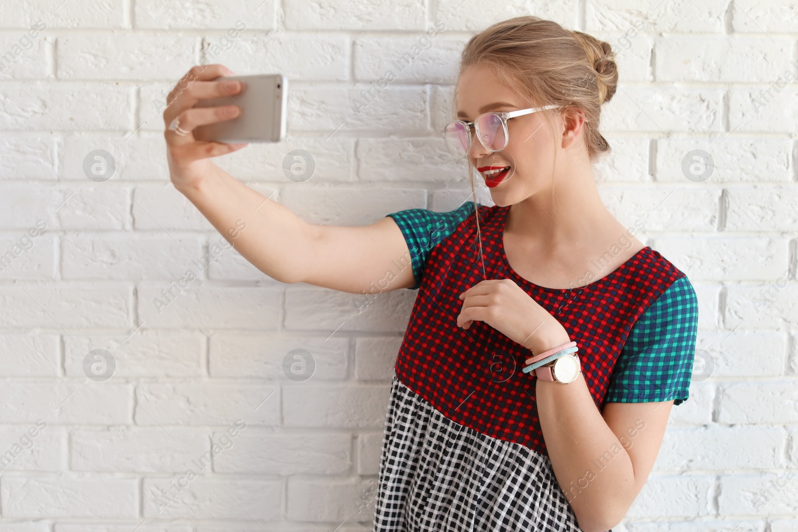 Photo of Attractive young woman taking selfie near brick wall