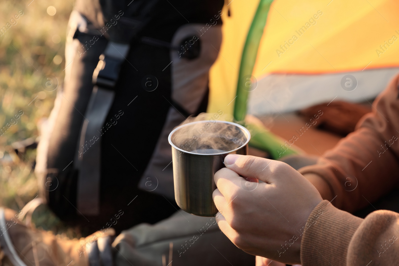 Photo of Man with cup of hot drink in camping tent, closeup