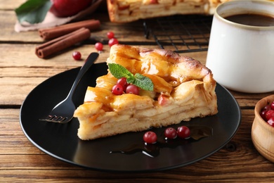 Photo of Slice of traditional apple pie with berries served on wooden table, closeup