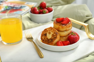 Photo of Tasty breakfast served in bedroom. Cottage cheese pancakes with strawberries and honey on white tray