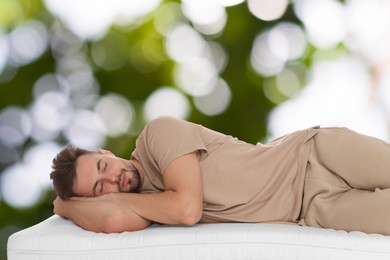 Image of Man sleeping on comfortable mattress against blurred green background, bokeh effect. Sleep well - stay healthy