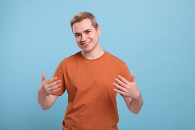 Photo of Happy man inviting to come in against light blue background
