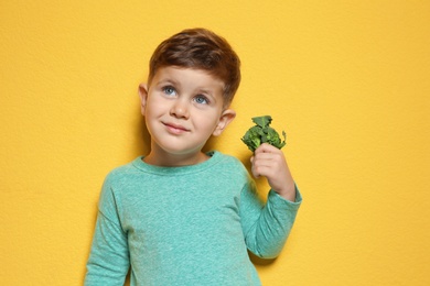 Photo of Adorable little boy with broccoli on color background. Space for text