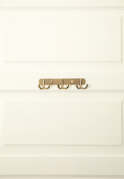 Photo of White door with empty metal clothes hooks