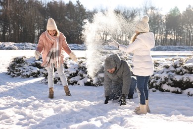 Happy family playing with snow in sunny winter park