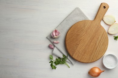 Photo of Cutting board, parsley, garlic and onion on white wooden table, flat lay. Space for text