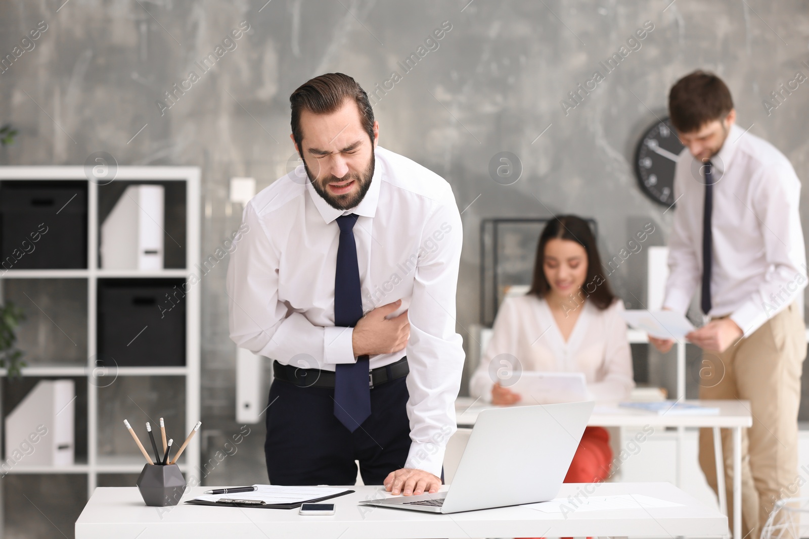 Photo of Young man suffering from stomach ache in office