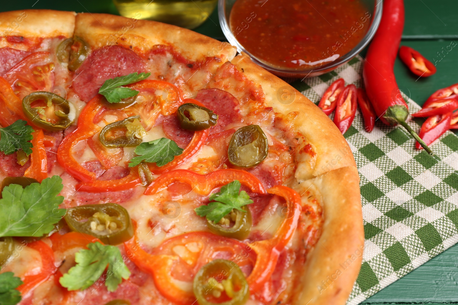 Photo of Delicious pizza Diablo and ingredients on green wooden table, closeup