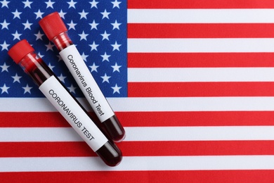 Test tubes with blood samples on American flag, flat lay. Coronavirus pandemic in USA