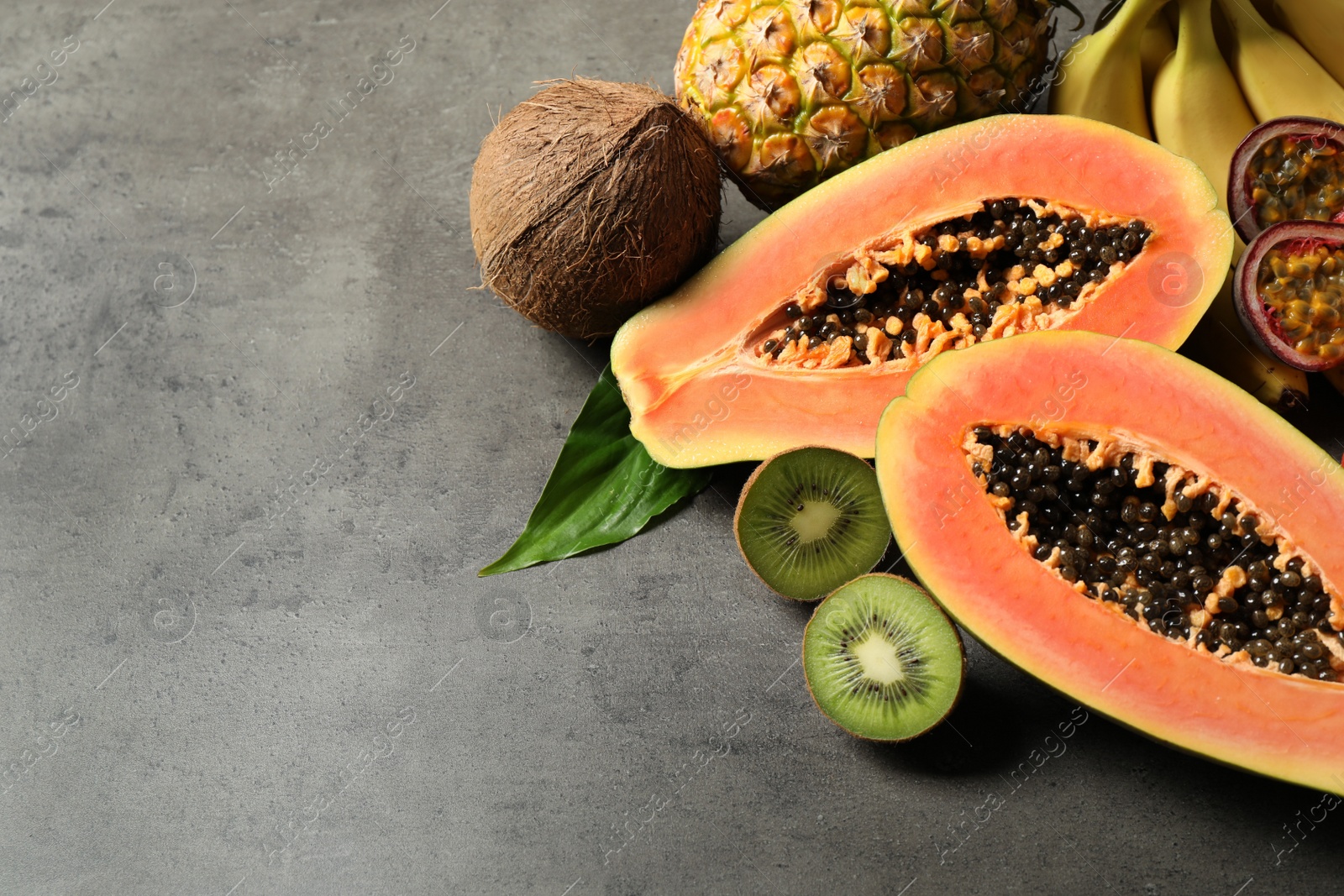 Photo of Fresh ripe papaya and other fruits on grey table. Space for text