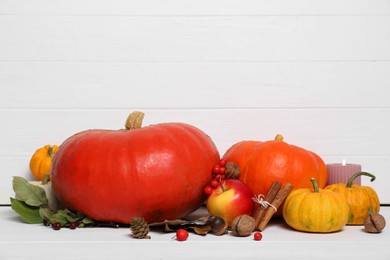 Photo of Happy Thanksgiving day. Beautiful composition with pumpkins and burning candle on white wooden table, space for text