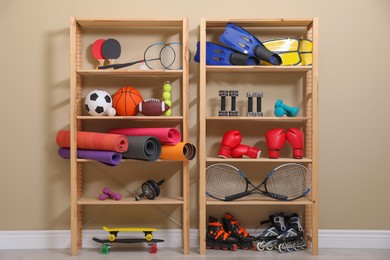 Shelving unit with different sports equipment near beige wall indoors