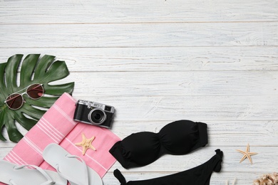 Flat lay composition with beach accessories on wooden background. Space for text