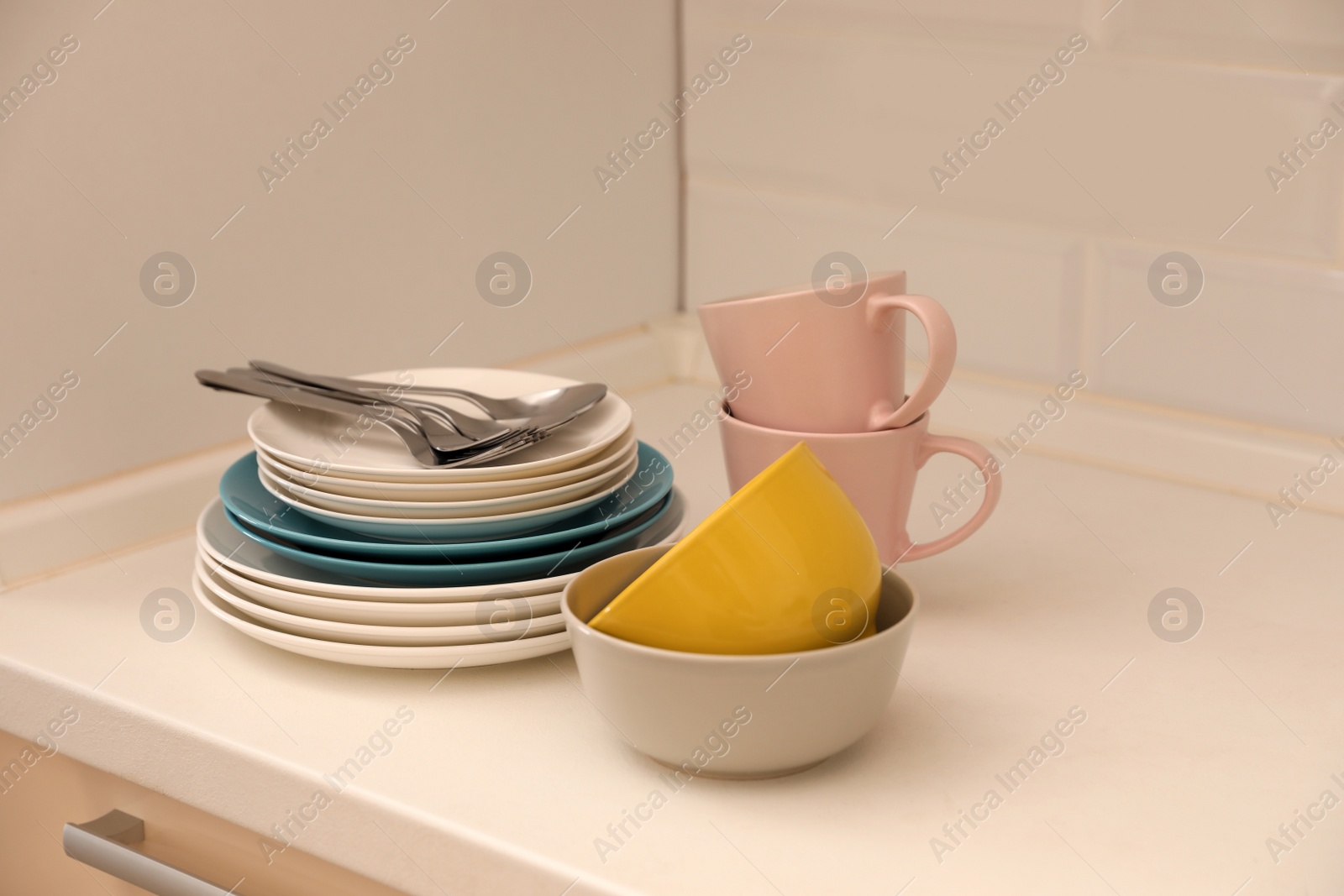 Photo of Clean dishware and cutlery on counter in kitchen