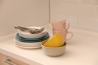 Photo of Clean dishware and cutlery on counter in kitchen