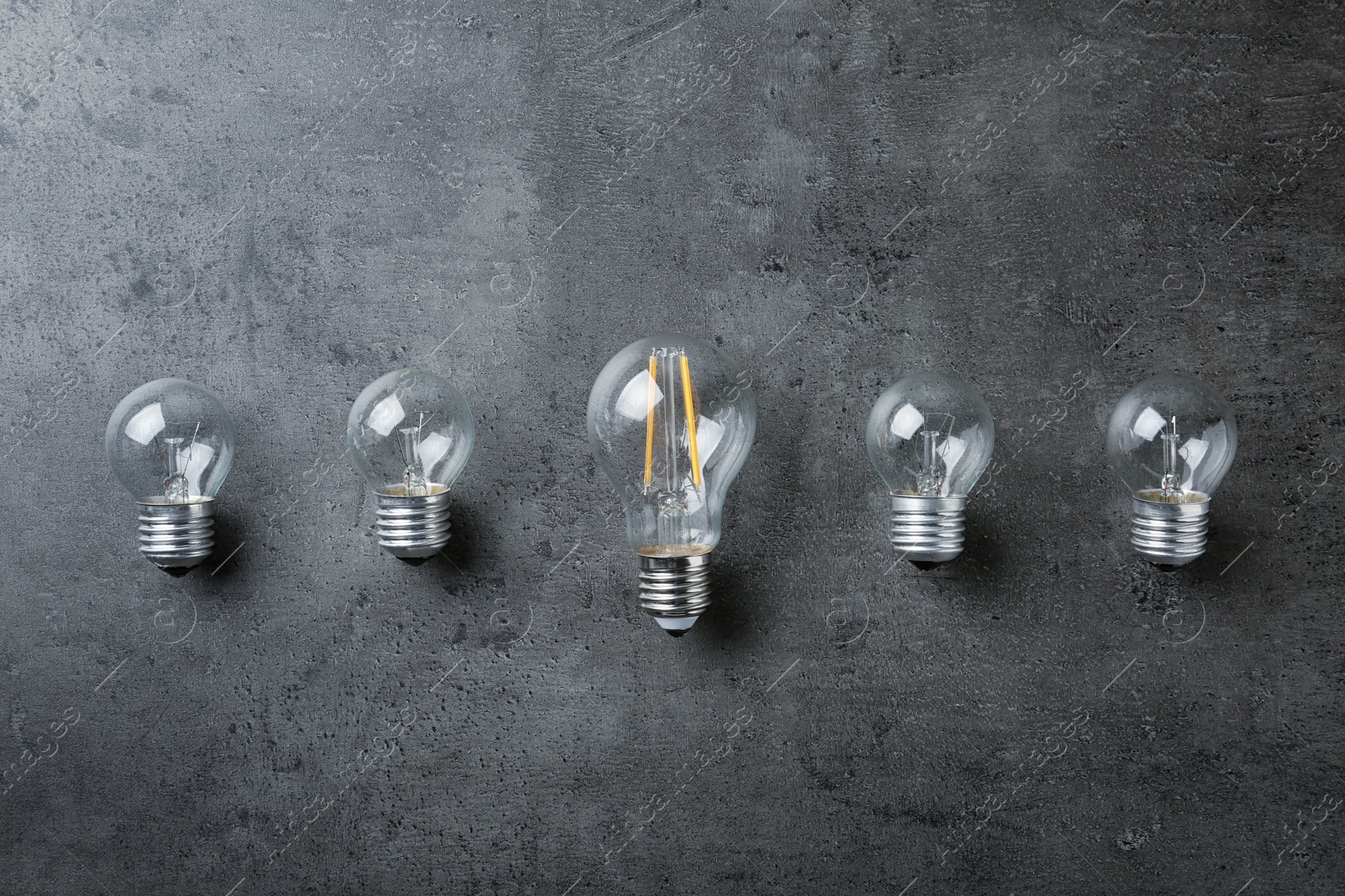 Photo of Vintage and modern lamp bulbs on grey stone surface, top view