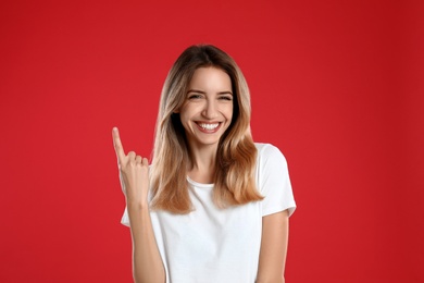 Woman showing number one with her hand on red background