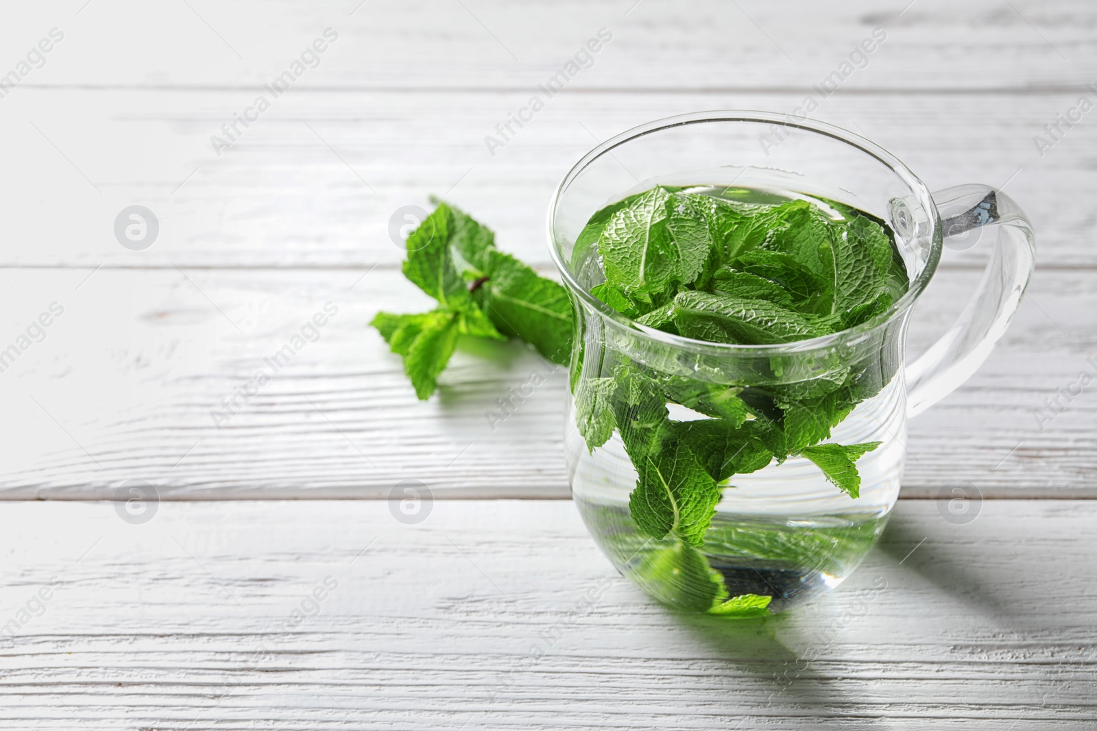 Photo of Cup with hot aromatic mint tea on wooden table