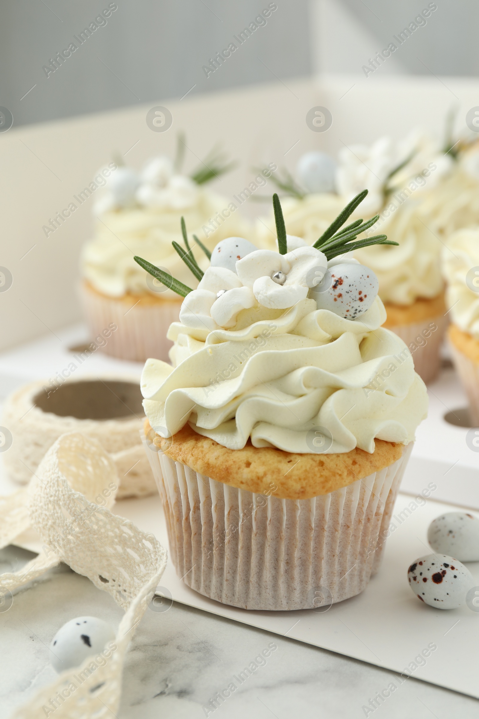 Photo of Tasty Easter cupcakes with vanilla cream on white marble table