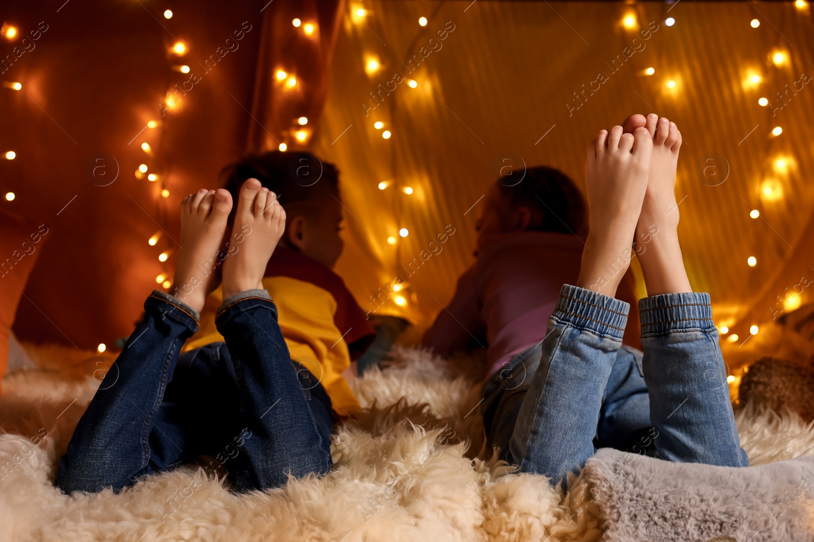 Photo of Kids in decorated play tent at home, back view