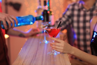 Young woman with glass of martini cocktail in bar, closeup. Space for text