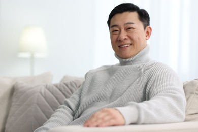 Portrait of smiling man on sofa indoors. Space for text