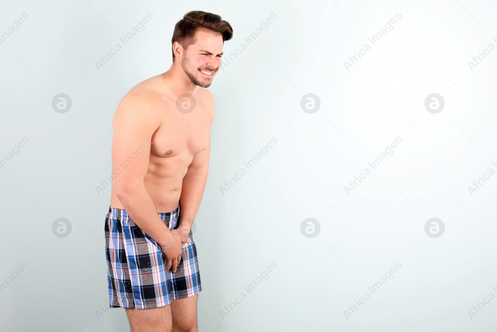 Photo of Young man with urological problems suffering from pain on color background