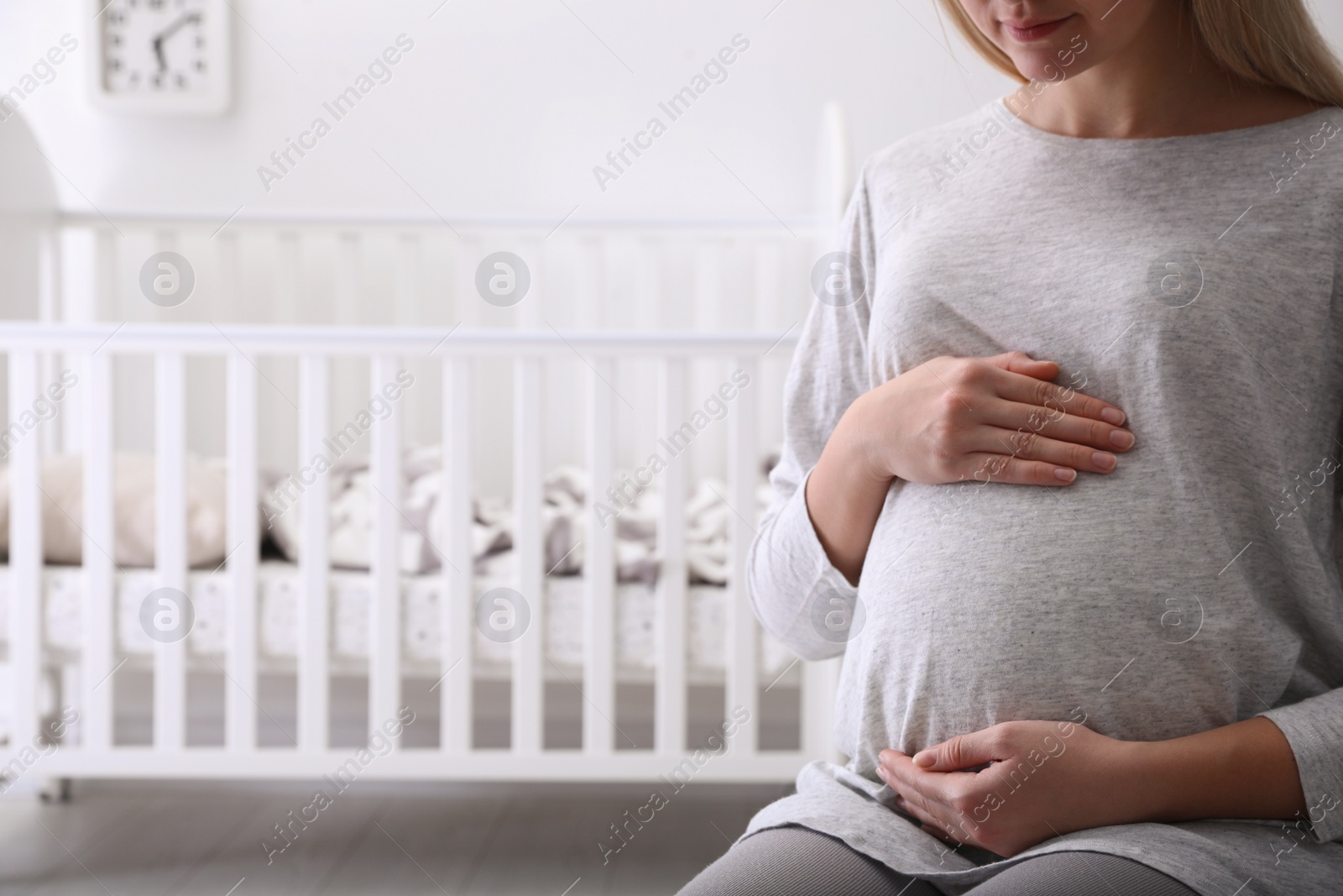 Photo of Pregnant woman in baby room, closeup view. Space for text