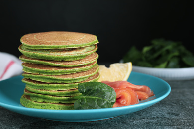 Tasty spinach pancakes with salmon on grey table, closeup