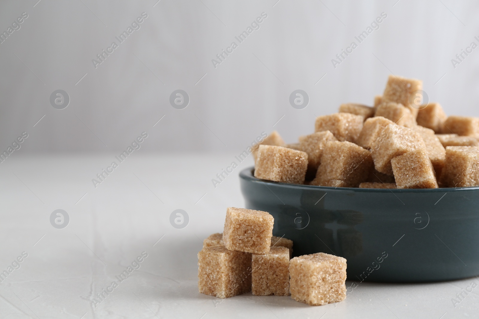 Photo of Brown sugar cubes on light table, closeup. Space for text