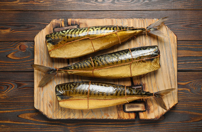 Tasty smoked fish on wooden table, top view