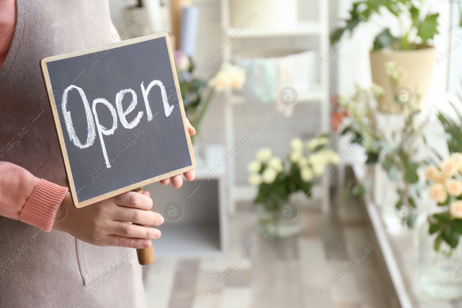 Photo of Female florist holding OPEN sign at workplace