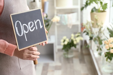 Female florist holding OPEN sign at workplace