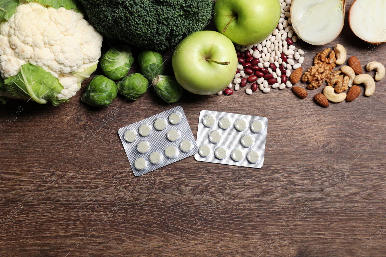 Photo of Blisters of pills and foodstuff on wooden table, flat lay. Space for text. Prebiotic supplements