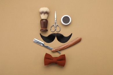 Photo of Artificial moustache and barber tools on beige background, flat lay