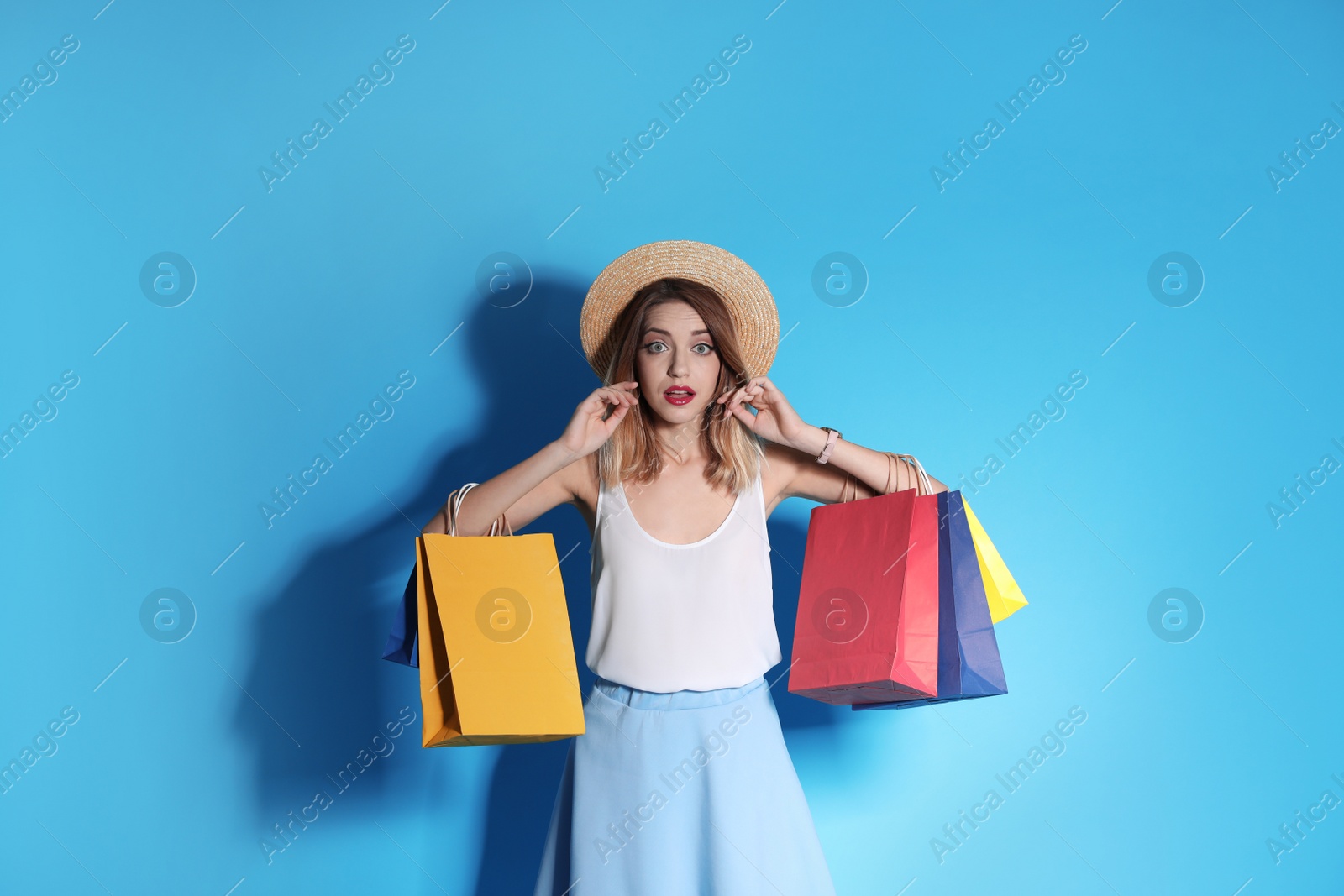 Photo of Beautiful young woman with shopping bags on color background