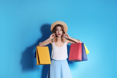 Photo of Beautiful young woman with shopping bags on color background