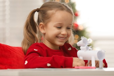 Photo of Cute little girl with paper toy for Saint Nicholas day at home