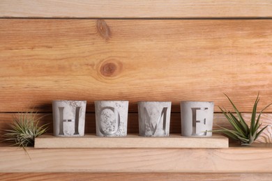 Photo of Tillandsia plants and word Home made with candles on wooden shelf, space for text. House decor